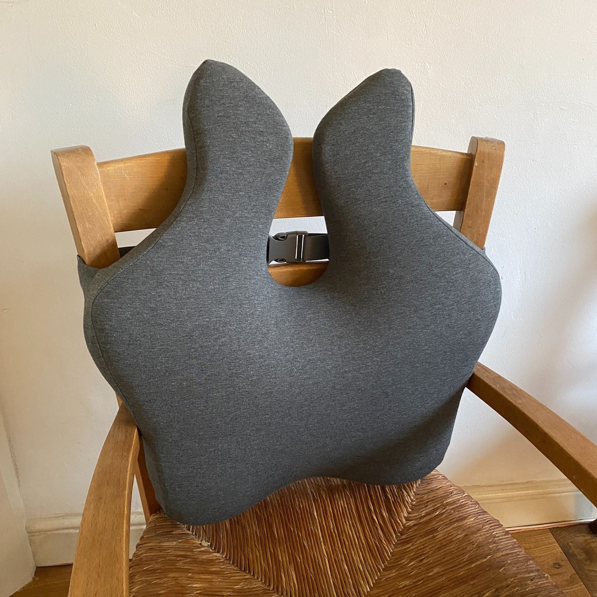 Grey seat cushion on a wooden chair against a white wall